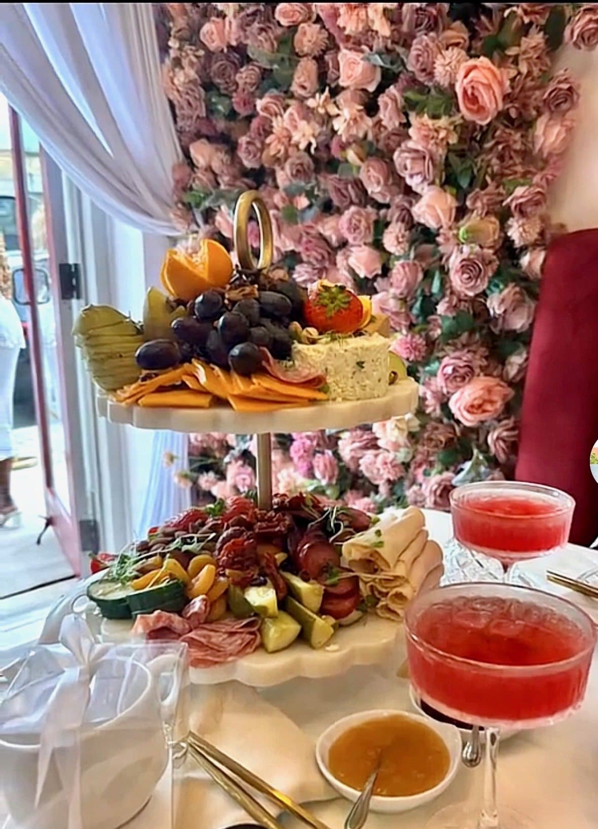 A two-tier charcuterie tower with artisanal cheeses, cured meats, and seasonal fruit