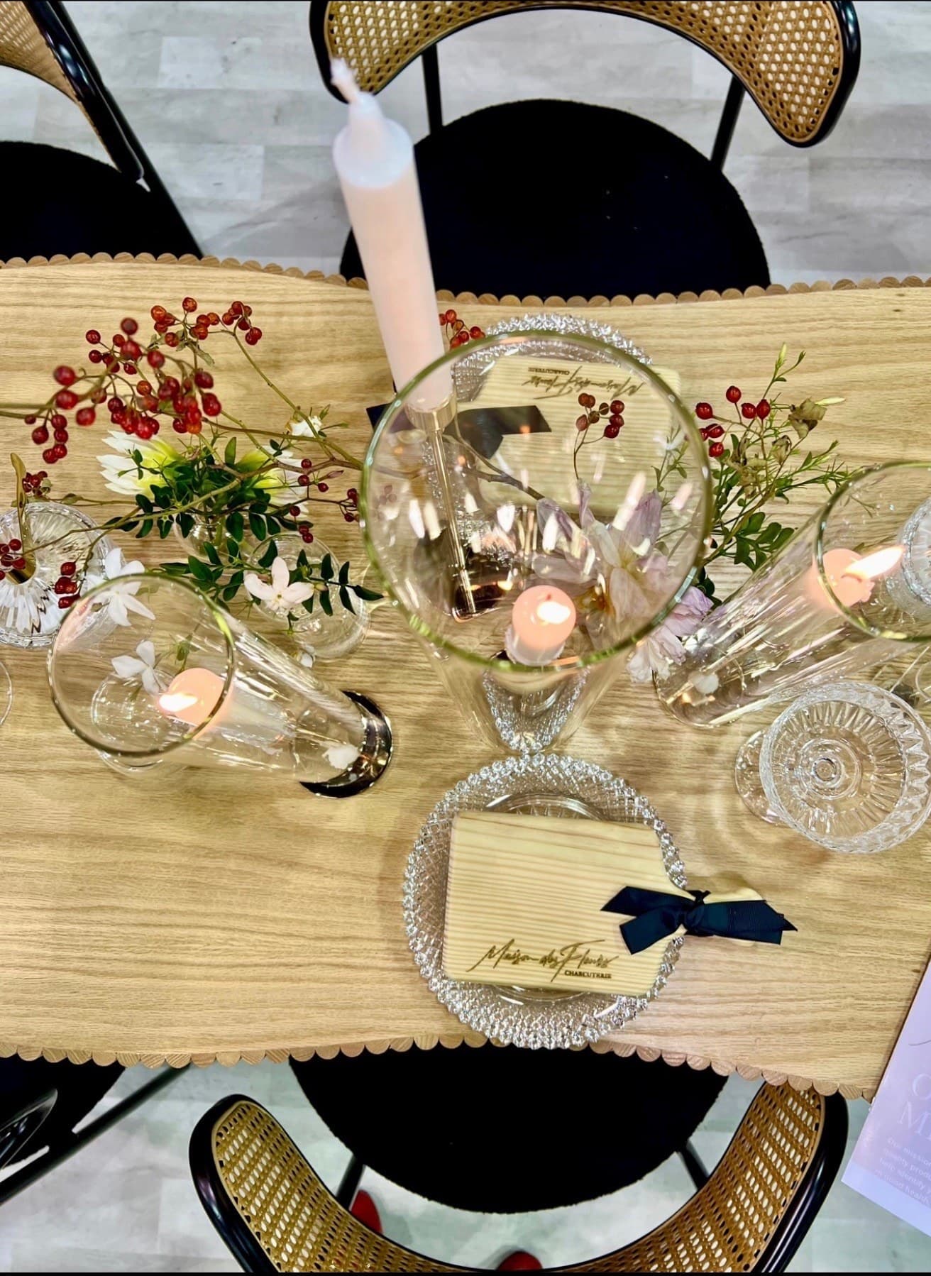 An elegant table setting with candlelight, florals, and a Maison des Fleurs place card