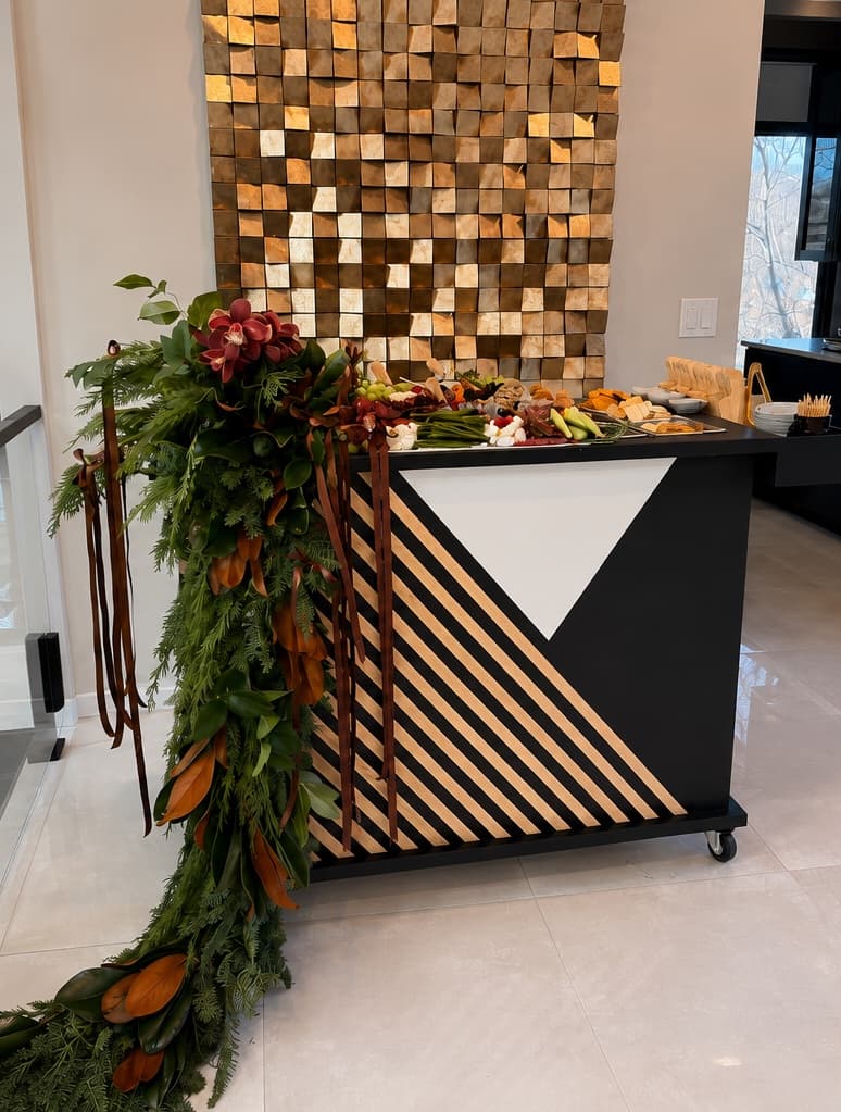 A styled Maison serving cart draped with winter garland beneath a wood-block accent wall