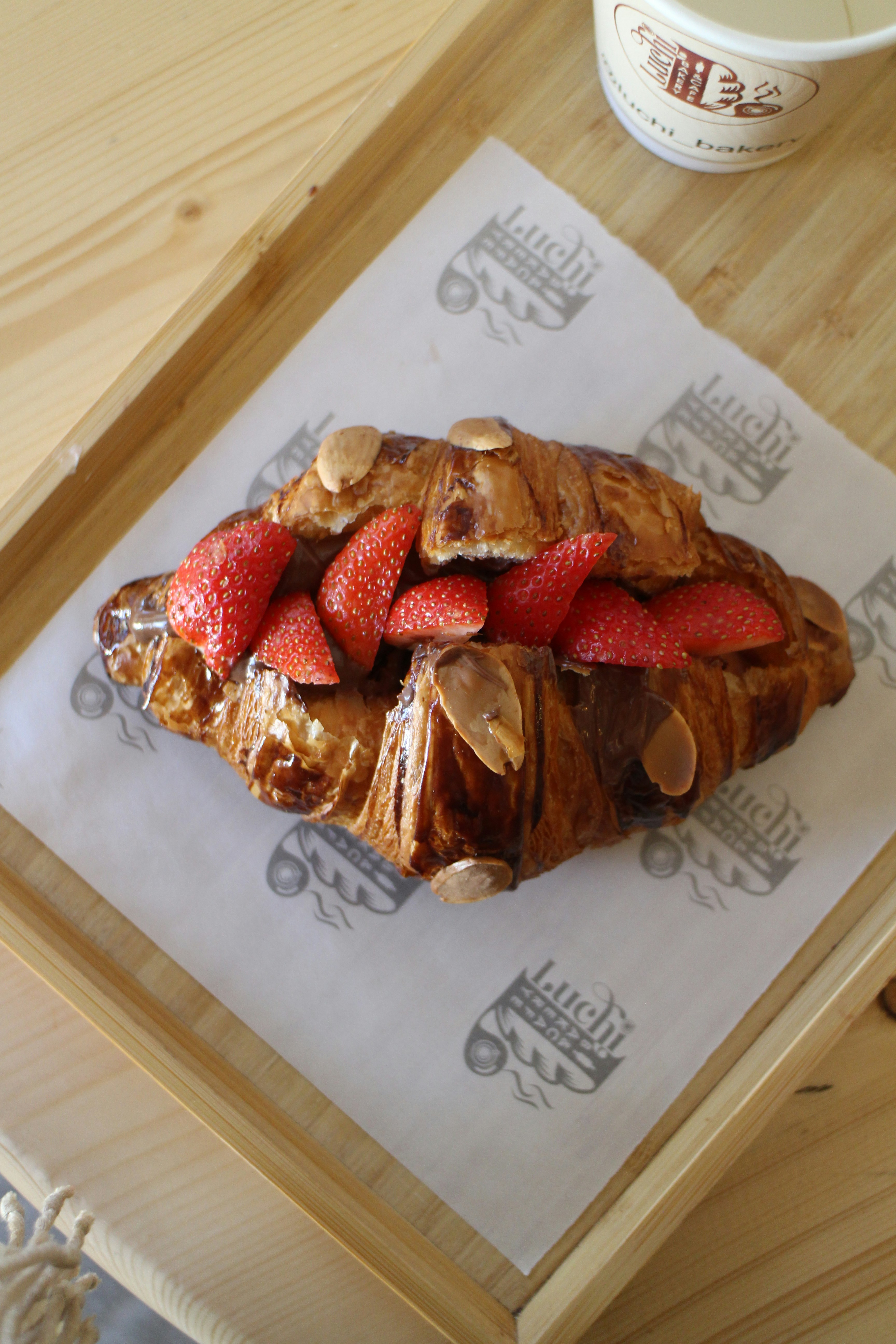 Almond croissant topped with sliced almonds and fresh strawberries